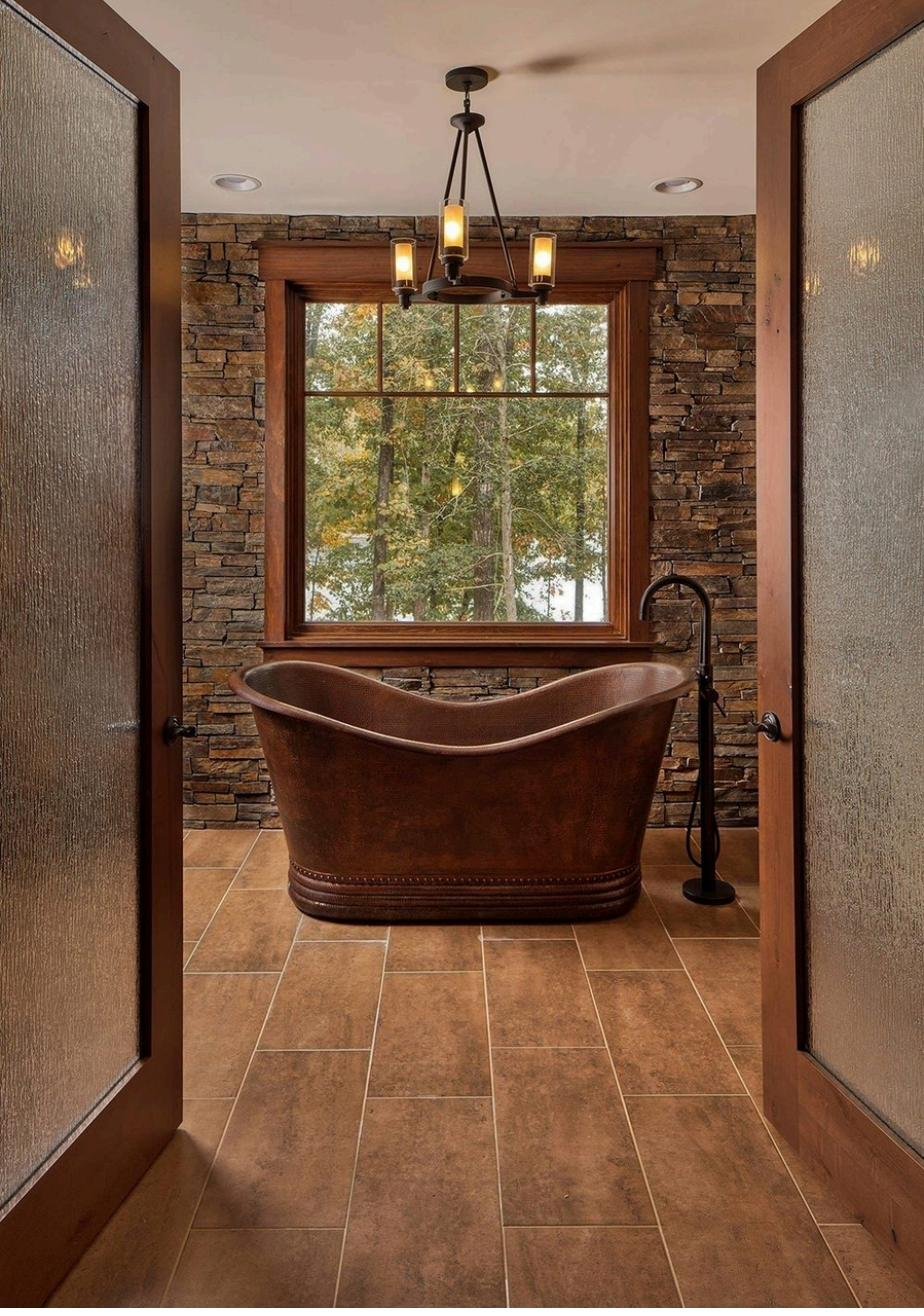 Freestanding copper soaking tub in stone bathroom