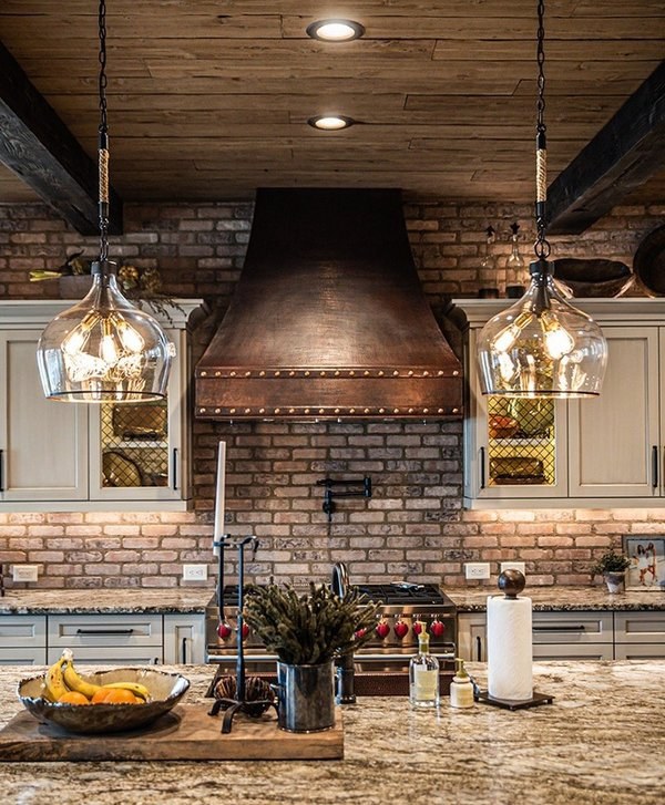 Hand-hammered copper range hood in kitchen with brick backsplash